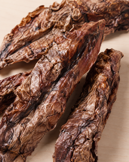 Strips of dried beef jerky arranged on a light beige surface.