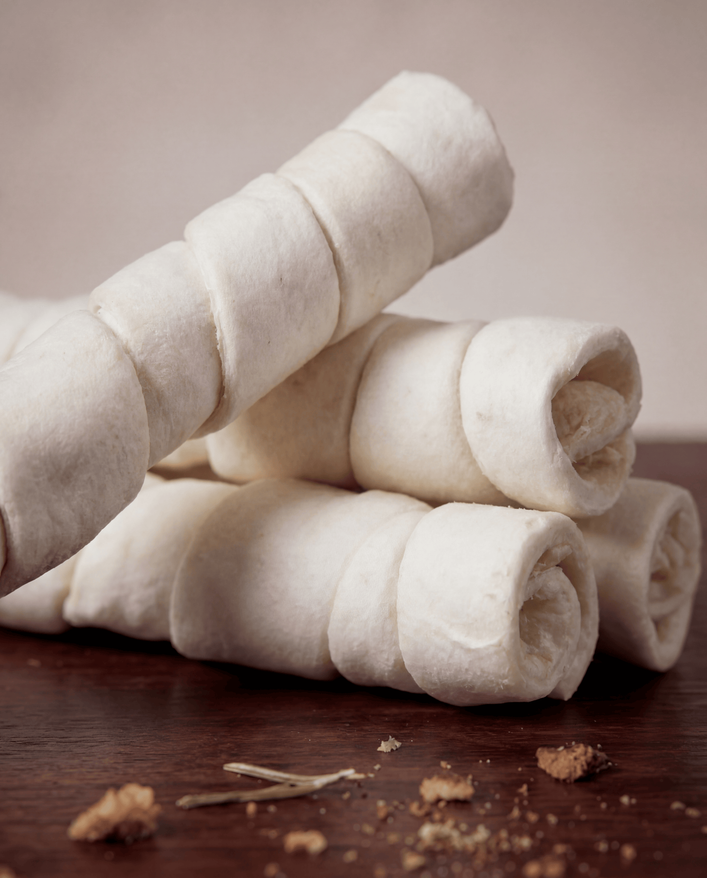 Stack of Allgood Chews - Beef Cheek Rolls on a wooden surface with a blurred background