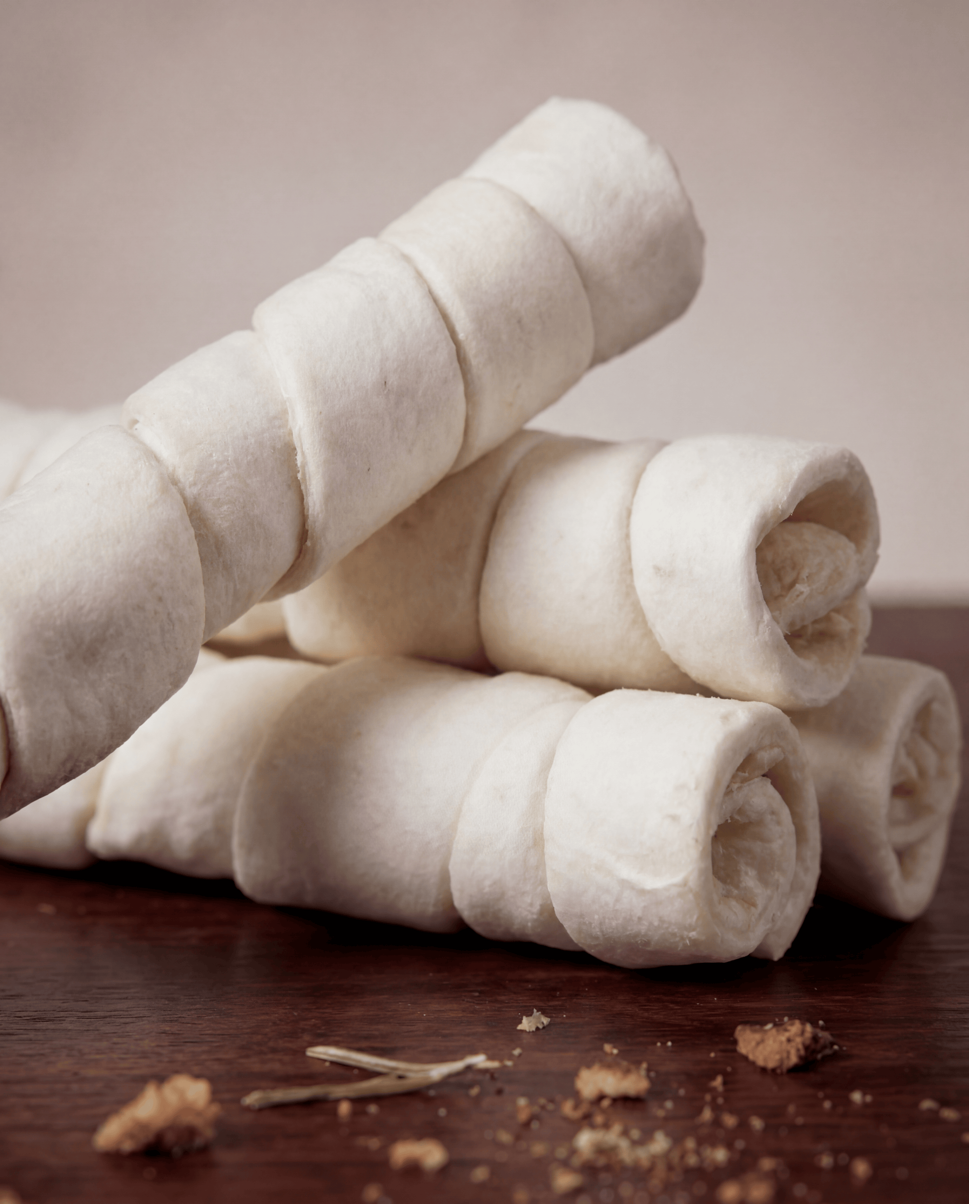 Stack of Allgood Chews - Beef Cheek Rolls on a wooden surface with a blurred background
