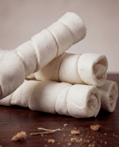 Stack of Allgood Chews - Beef Cheek Rolls on a wooden surface with a blurred background