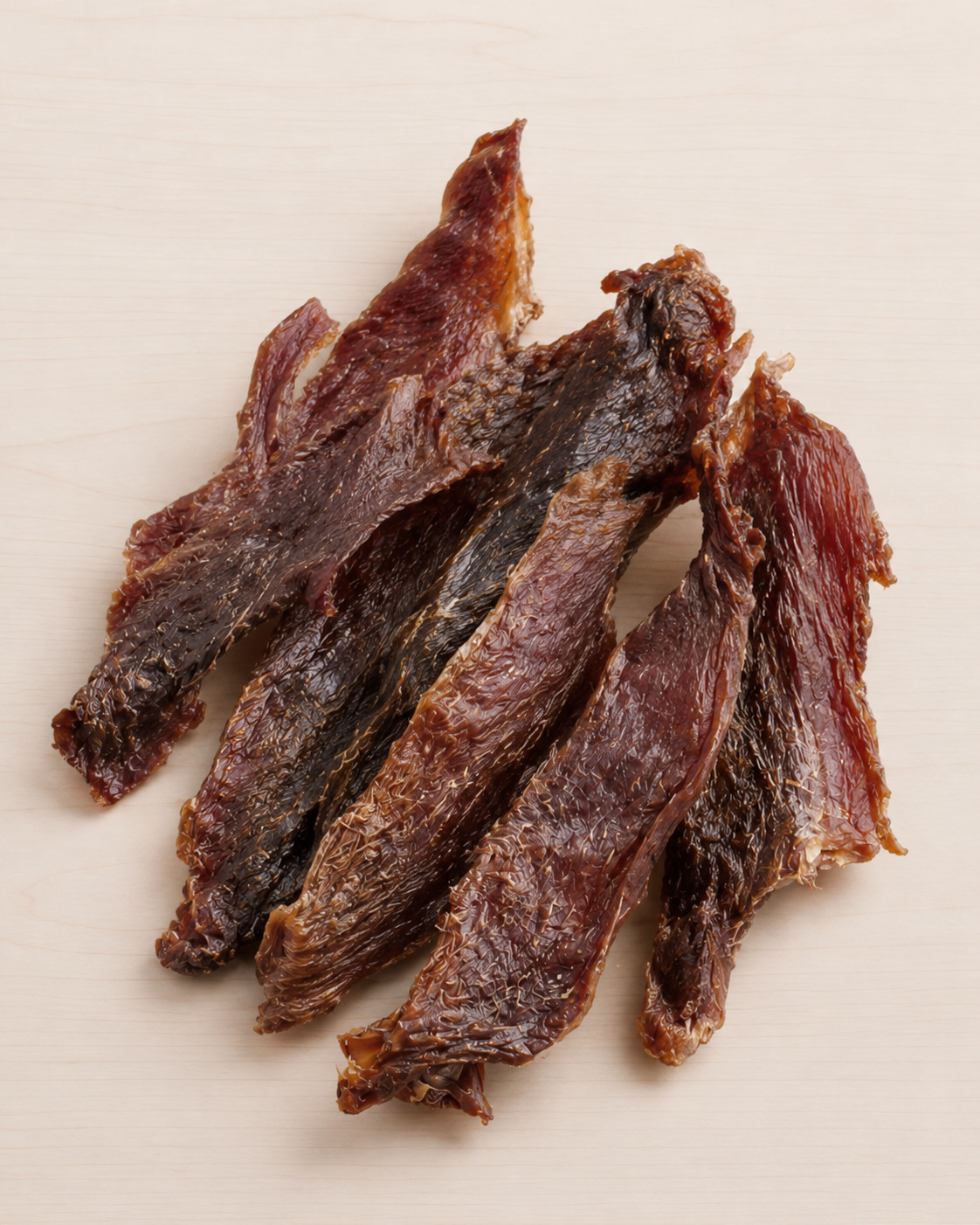 Several strips of duck jerky arranged on a light beige surface.