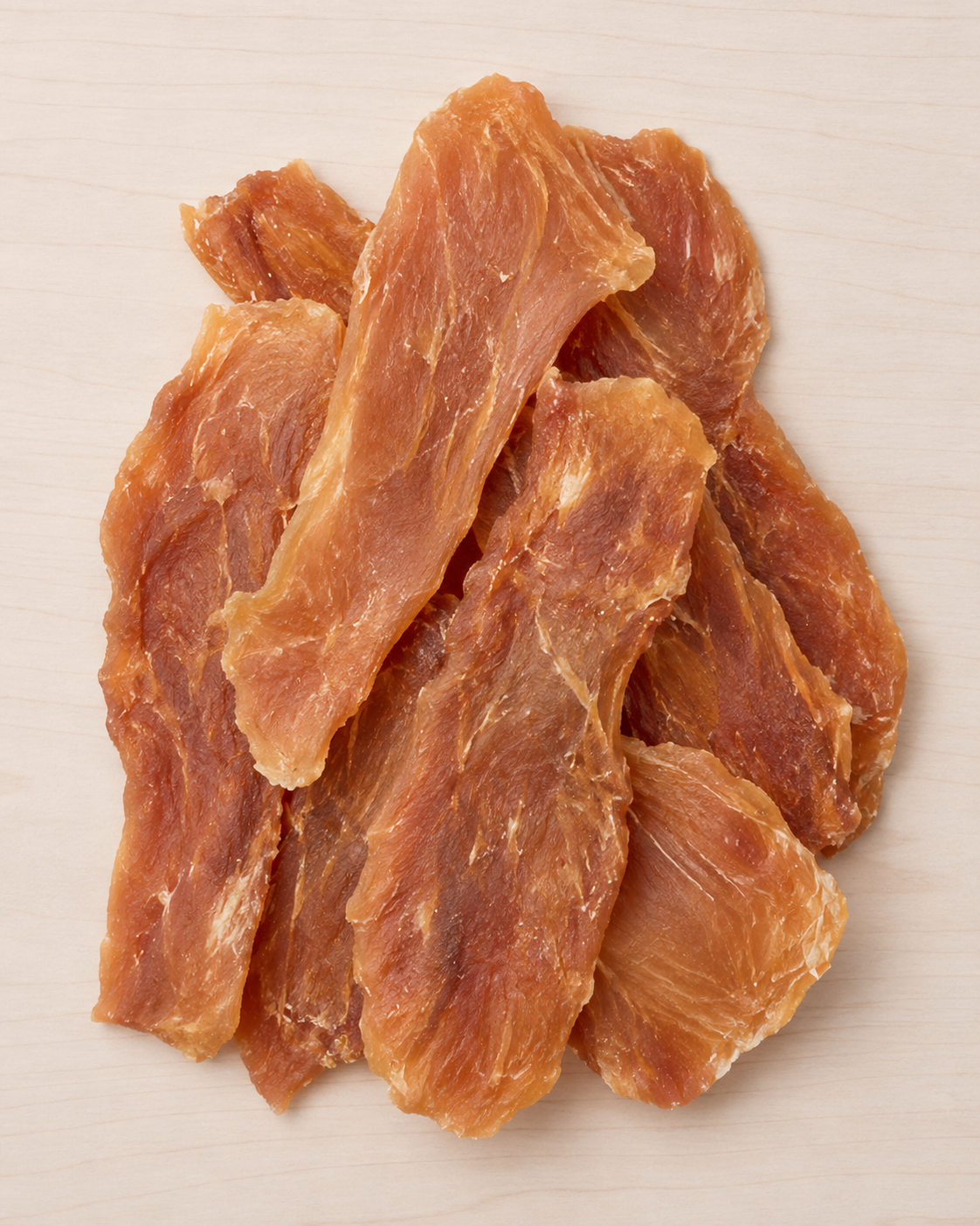 Allgood chicken jerky  pieces arranged on a light beige surface.